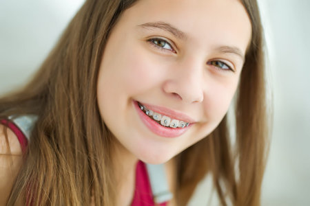Close up portrait of smiling teenager girl showing dental braces.Isolated on white background. High quality photo.の写真素材