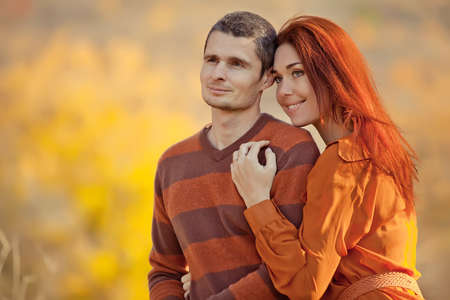 Beautiful couple man woman in love. Smiling laughing guy and girl hugging in the park on an autumn fall day. High quality photo.の写真素材