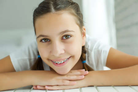 Close up portrait of smiling teenager girl showing dental braces.Isolated on white background. High quality photo.の写真素材