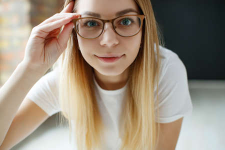 A woman has vision problems, squints when trying to see something, takes off her glasses, is isolated. Myopia, hyperopia, vision concept. High quality photo.の写真素材
