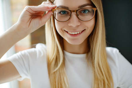 A woman has vision problems, squints when trying to see something, takes off her glasses, is isolated. Myopia, hyperopia, vision concept. High quality photo.の写真素材