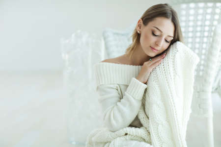 Young woman relaxing with chunky wool blanket. Relax, comfort lifestyle. Winter style. High quality photo.の写真素材