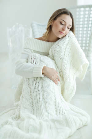Young woman relaxing with chunky wool blanket. Relax, comfort lifestyle. Winter style. High quality photo.の写真素材