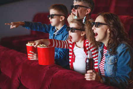 Family mom father and children are watching a projector, TV, cinema, movies with popcorn in the cinema. High quality photo.の写真素材