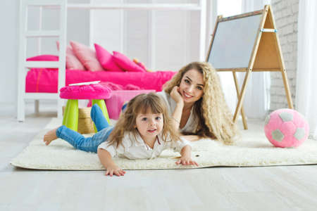 Happy loving family. Mother and daughter in the childrens room. Funny mom and lovely baby having fun indoors. Cute little girl is playing with a woman. High quality photo.の写真素材