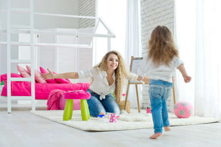 Happy loving family. Mother and daughter in the childrens room. Funny mom and lovely baby having fun indoors. Cute little girl is playing with a woman. High quality photo.の写真素材