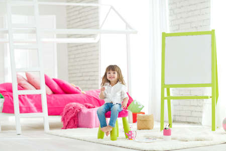 Cute little baby girl on the carpet at home. Funny lovely baby having fun in the nursery. High quality photo.の写真素材