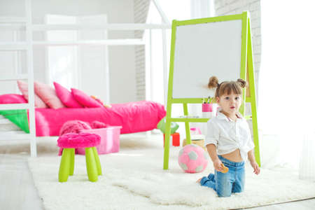 Cute little baby girl on the carpet at home. Funny lovely baby having fun in the nursery. High quality photo.の写真素材