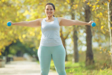 An attractive plus size woman in a sports top and leggings, goes in for sports, works out in a cozy city park. High quality photo.の写真素材