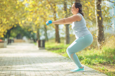 An attractive plus size woman in a sports top and leggings, goes in for sports, works out in a cozy city park. High quality photo.の写真素材
