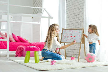 Happy loving family. Mother and daughter in the childrens room. Funny mom and lovely baby having fun indoors. Cute little girl is playing with a woman. High quality photo.の写真素材