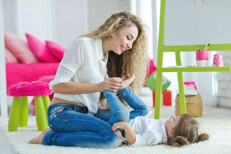 Happy loving family. Mother and daughter in the childrens room. Funny mom and lovely baby having fun indoors. Cute little girl is playing with a woman. High quality photo.の写真素材