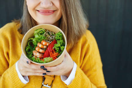 Portrait of a cheerful woman eating healthy salad. Concept of losing weight, sports and healthy eating. High quality photo.の写真素材