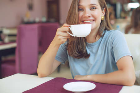 Thoughtful mature woman sits in a cafeteria holding a coffee mug. A middle-aged woman drinks tea while thinking. Relaxing and thinking while drinking coffee. High quality photo.の写真素材