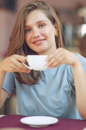 Thoughtful mature woman sits in a cafeteria holding a coffee mug. A middle-aged woman drinks tea while thinking. Relaxing and thinking while drinking coffee. High quality photo.の写真素材