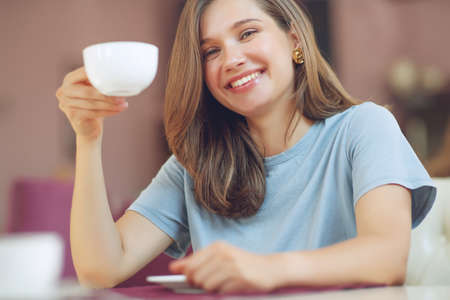 Thoughtful mature woman sits in a cafeteria holding a coffee mug. A middle-aged woman drinks tea while thinking. Relaxing and thinking while drinking coffee. High quality photo.の写真素材