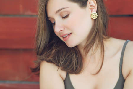 Close-up of a beautiful woman in shiny gold earrings. Portrait of a young woman in costume jewelry. High quality photo.の写真素材