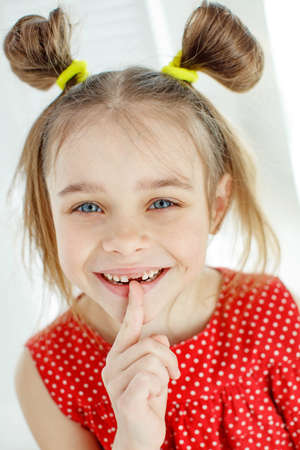 A little girl lost the first milk tooth. Loss of primary teeth. Childrens dentistry. High quality photo.の写真素材