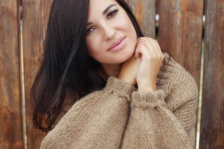 Outdoor atmospheric lifestyle photo of young beautiful lady. Brown hair and eyes. A warm sweater. Autumn vibrations. Softness, warmth and comfort. High quality photo.の写真素材