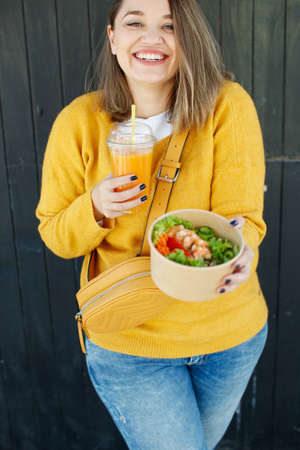 Portrait of a cheerful woman eating healthy salad. Concept of losing weight, sports and healthy eating. High quality photo.の写真素材