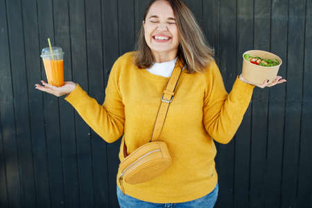 Portrait of a cheerful woman eating healthy salad. Concept of losing weight, sports and healthy eating. High quality photo.の写真素材