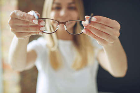 A woman has vision problems, squints when trying to see something, takes off her glasses, is isolated. High quality photo.の写真素材