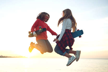 Two female friends playing with skateboard skateboard in the park. Girls with a skateboard. Laughter and fun. High quality photo.の写真素材