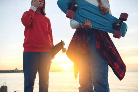 Two female friends playing with skateboard skateboard in the park. Girls with a skateboard. Laughter and fun. High quality photo.の写真素材