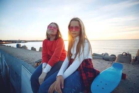 Two female friends playing with skateboard skateboard in the park. Girls with a skateboard. Laughter and fun. High quality photo.の写真素材