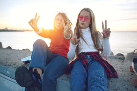 Two female friends playing with skateboard skateboard in the park. Girls with a skateboard. Laughter and fun. High quality photo.の写真素材