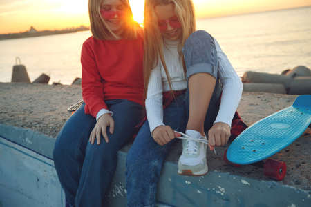 Two female friends playing with skateboard skateboard in the park. Girls with a skateboard. Laughter and fun. High quality photo.の写真素材