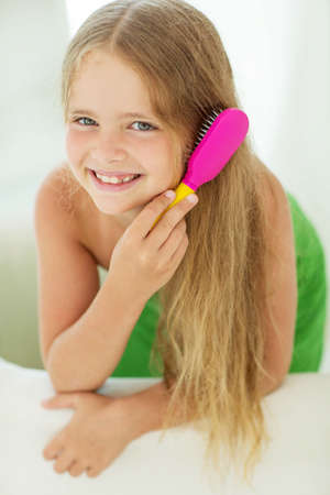 Little girl with long hair and comb in the hands of caring for her hair. High quality photo.の写真素材