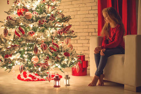 Happy Holidays. Cute little child near the Christmas tree. The girl laughs and enjoys Christmas. High quality photo.の写真素材