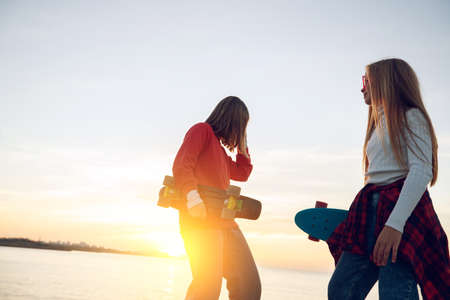 Two female friends playing with skateboard skateboard in the park. Girls with a skateboard. Laughter and fun. High quality photo.の写真素材
