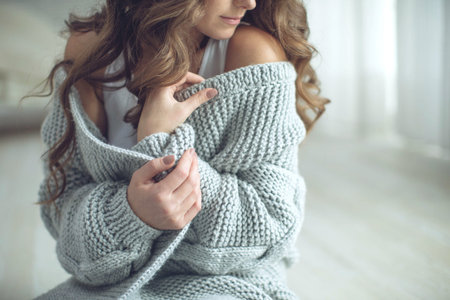 Young beautiful woman in warm knitted clothes at home. Female indoor portrait. High quality photo.
