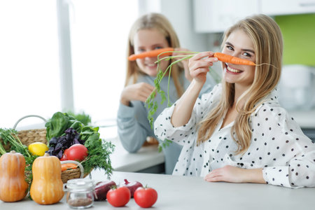 Healthy eating. Happy family mother and baby girl preparing vegetarian vegetable salad at home in...