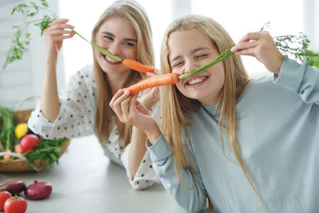 Healthy eating. Happy family mother and baby girl preparing vegetarian vegetable salad at home in the kitchen. High quality photo.の写真素材