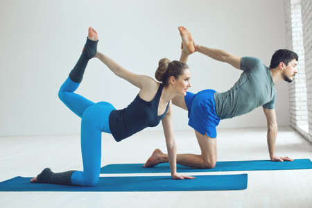 Beautiful couple in sportswear is stretching on a yoga mat while exercising from the home. High quality photo.の写真素材