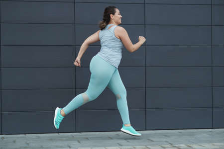 Fat woman jogging, doing sports for weight loss, obesity problem. High quality photo.の写真素材