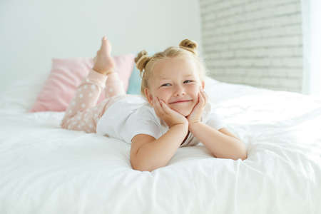 Nice baby girl enjoys a sunny morning. Good morning at home. The girl wakes up from sleep. High quality photo.の写真素材