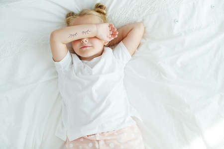 Nice baby girl enjoys a sunny morning. Good morning at home. The girl wakes up from sleep. High quality photo.の写真素材