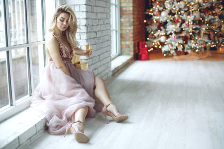 Party, drinks, holidays, people and celebration concept - smiling woman in beautiful dress with glass of sparkling wine and champagne over Christmas tree lights background. High quality photo.の写真素材