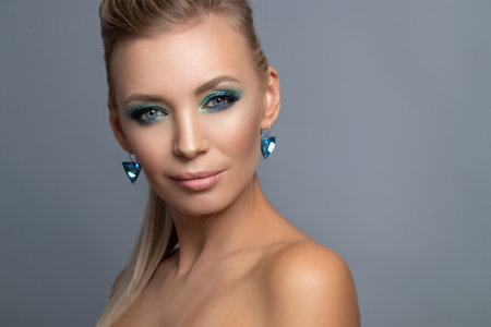 Hairstyle of a blonde high ponytail. Beauty Fashion Woman Portrait. Beautiful girl model with makeup, earrings and a ring, posing, isolated on studio background. High quality photo.の写真素材