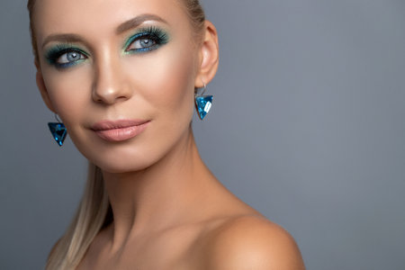 Hairstyle of a blonde high ponytail. Beauty Fashion Woman Portrait. Beautiful girl model with makeup, earrings and a ring, posing, isolated on studio background. High quality photo.の写真素材