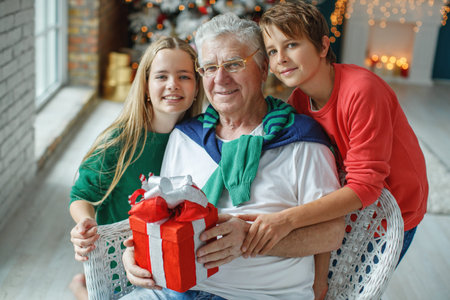 Grandfather and grandchildren in a room decorated for Christmas against the background of a...