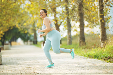 Fat woman jogging, doing sports for weight loss, obesity problem. High quality photo.の写真素材