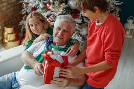 Grandfather and grandchildren in a room decorated for Christmas against the background of a Christmas tree. Christmas holiday concept. contrast photography. High quality photo.の写真素材