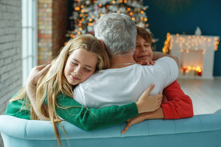 Grandfather and grandchildren in a room decorated for Christmas against the background of a...