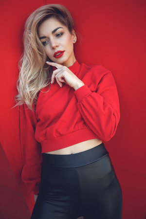 Fashion portrait of a beautiful woman in style over red background. High quality photo.の写真素材