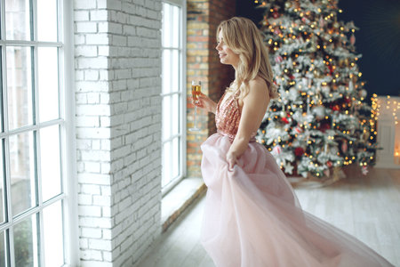 Party, drinks, holidays, people and celebration concept - smiling woman in beautiful dress with glass of sparkling wine and champagne over Christmas tree lights background. High quality photo.の写真素材